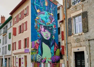 fresque sur un mur en retrait de la rue représentant une fille extra-terrestre, dans les tons de bleu, de vert avec des touches de rouge et d'orange