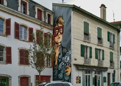 dans un mur en retrait une fresque , toute verticale, représentant un garçon avec un masque rouge accompagné de son doudou