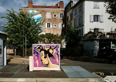 Personnage emblématique (Exist) peint sur un grand coffret Telecom, installé sur un trottoir de la ville : quartier St Esprit