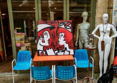 sur le devant d'une boutique de brocanteur, au cour du quartier, Grand Bayonne, une Toile est exposée sur table, entourée de chaise en plastique bleu